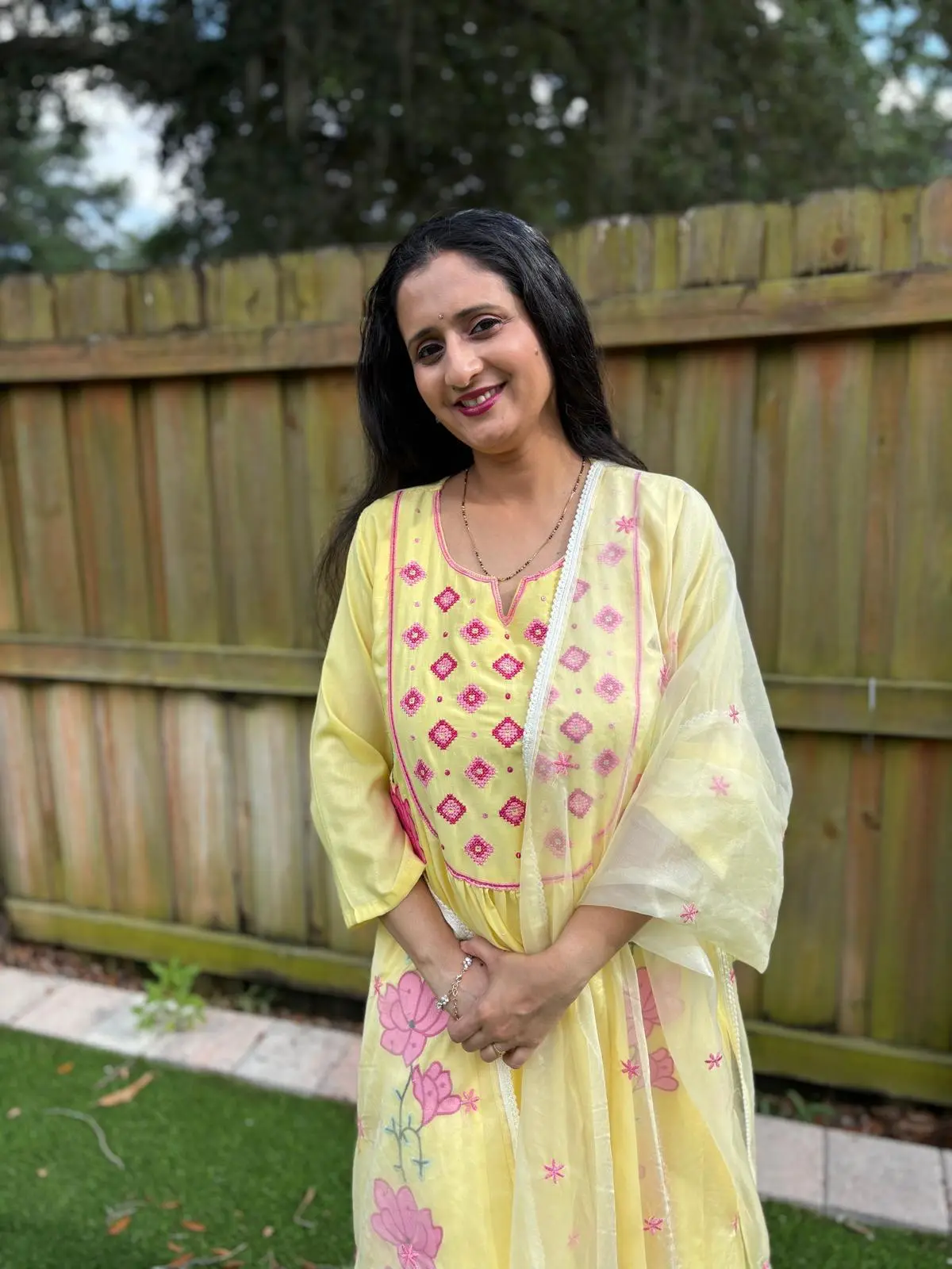 Manali Phadke, co-founder of Manaswini Arts, smiling in a yellow kurta with pink embroidery.